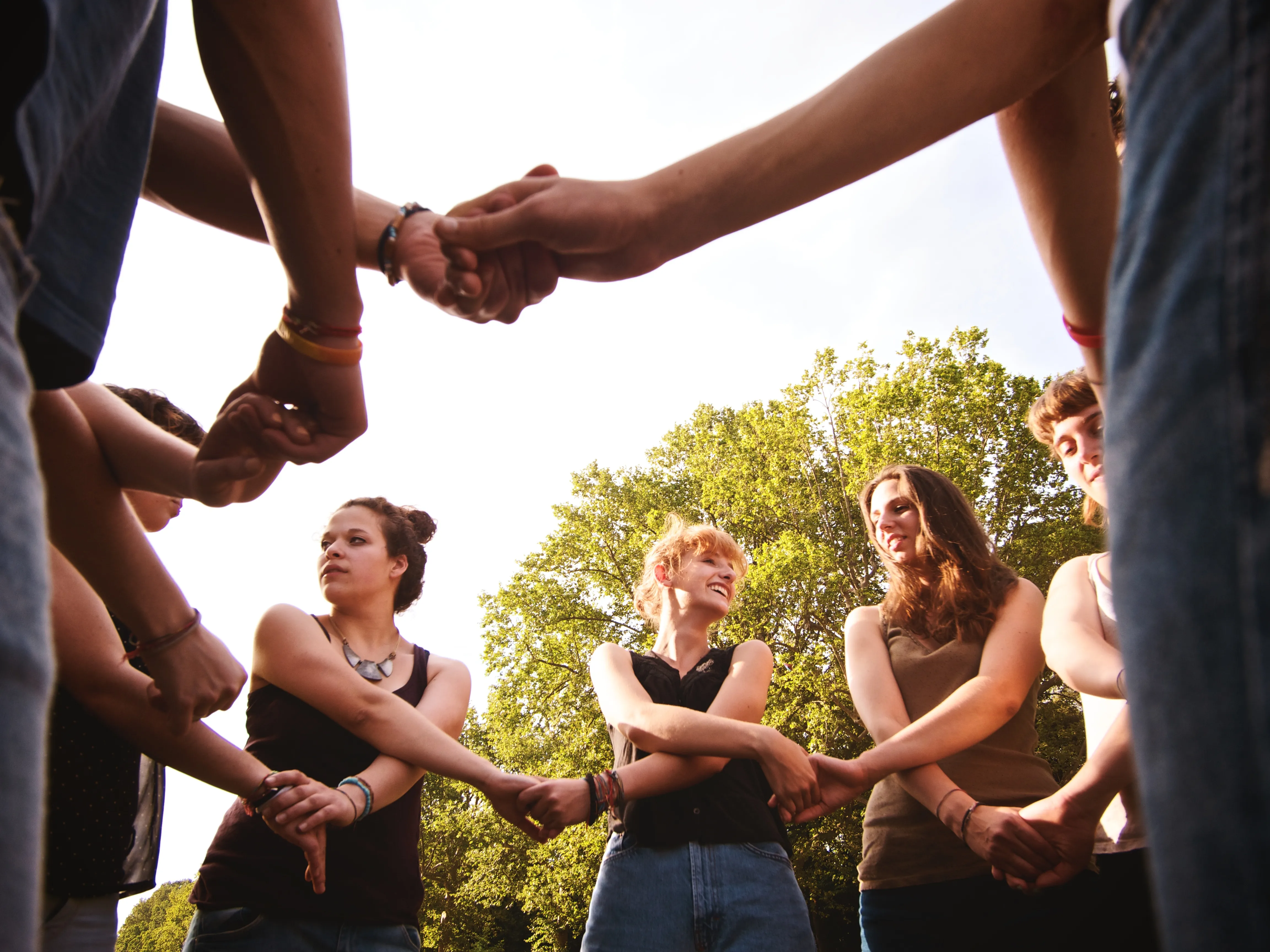 Un grupo de personas de pie se dan la mano en un día soleado