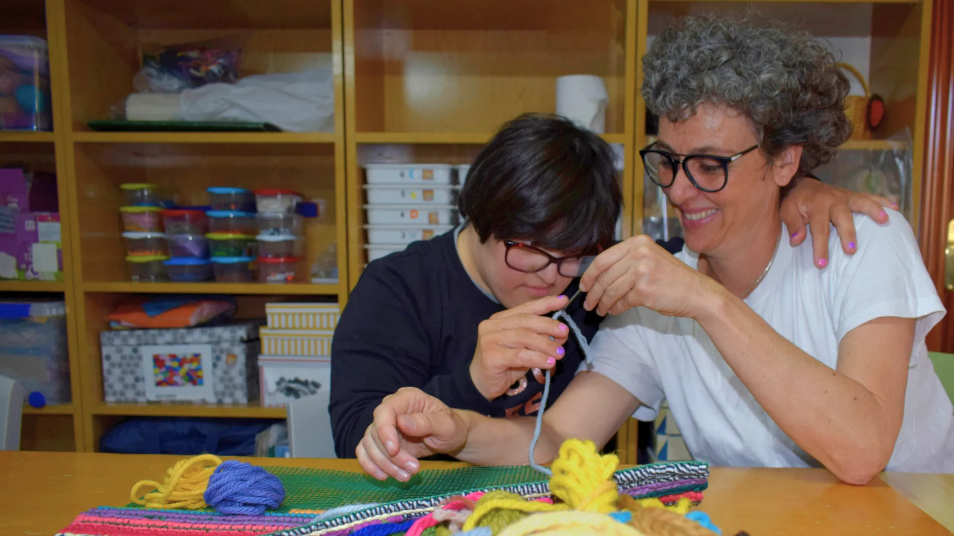 trabajadora de Hospitalarias Fundación Purísima Concepción junto a un niño con síndrome de Down en un taller de manualidades